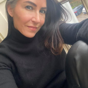 Stella Dove sits with her back to a window, wearing a black roll-neck sweater and leather trousers, long silver-streaked hair framing a gentle smile. You Do Not Have To Be Good — a lyrical reflection on belonging, softness, and the permission to simply be.