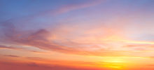 imagem: céu em tons laranja com o nascer do sol entre nuvens