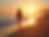 A woman walking along the beach at sunset