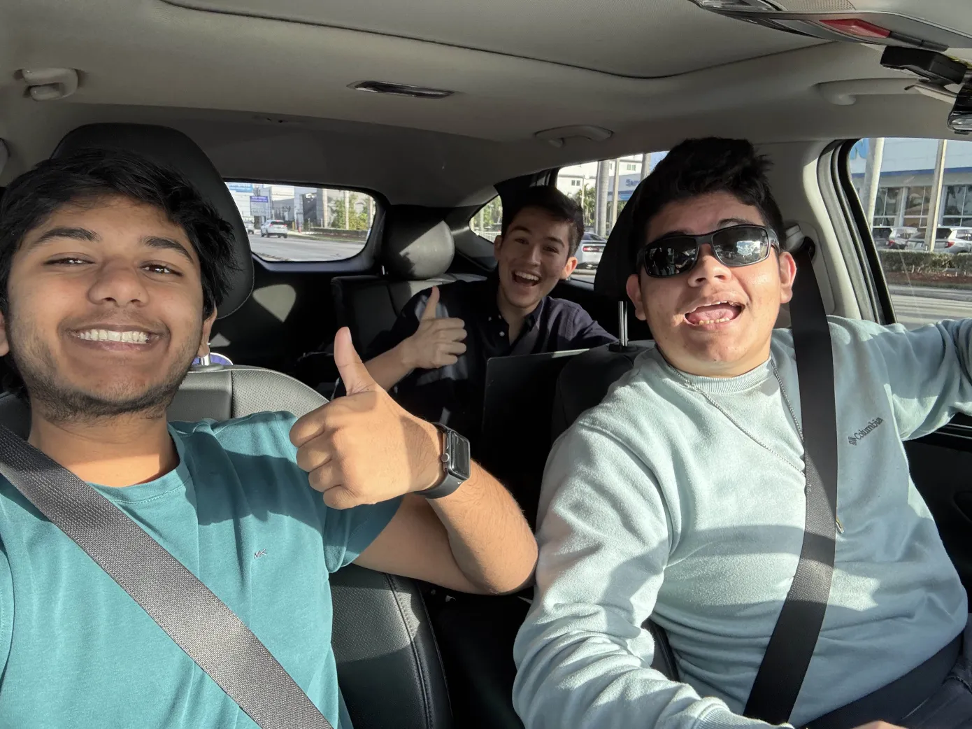 Victor, Camilo, and Yatin posing while driving to the children's hospital to drop off the baskets for the Palm Beach Outreach 2025 Volunteer childrens hospital basket drive