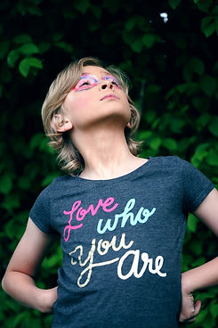 Gender fluid child wearing t-shirt saying "Love who you are"