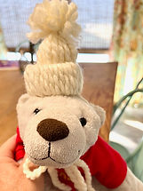 White stuffed polar bear toy wearing decorative hat craft.