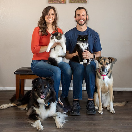 two people pose for a photo with two cats and two dogs