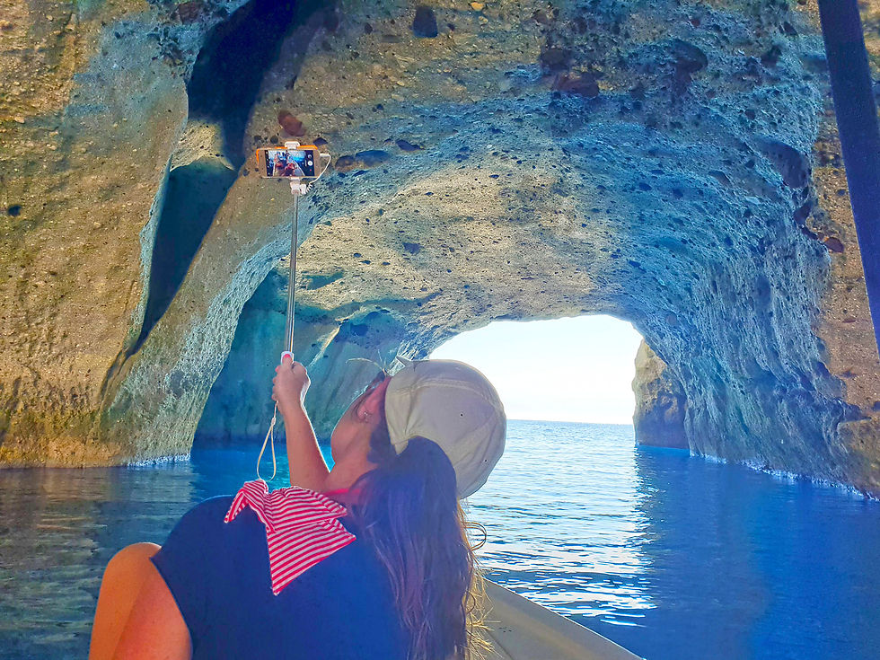 Pohled z úrovně moře na loď plující kolem skalnatého pobřeží Milosu