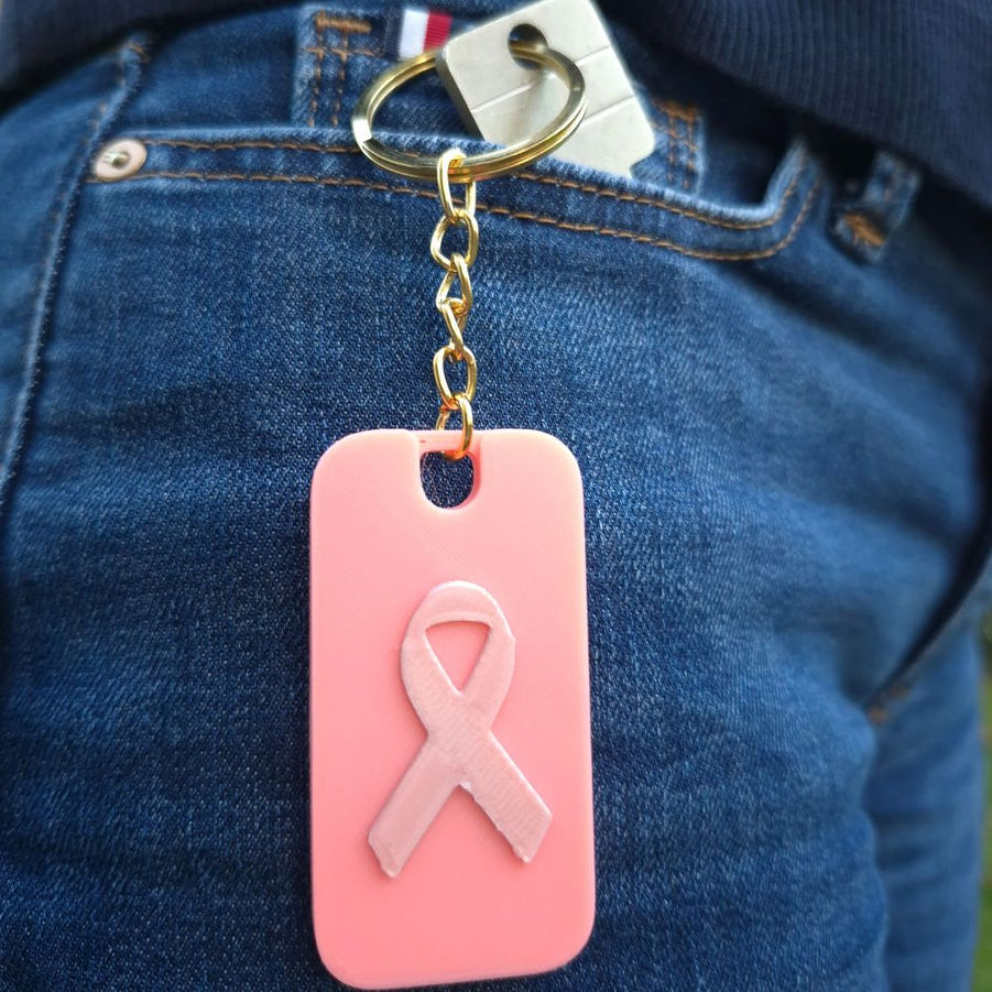 Sifflet Octobre Rose phosphorescent accroché à un jean
