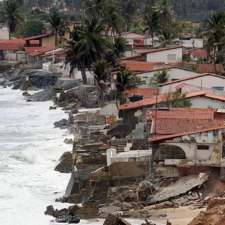A imagem retrata a erosão costeira e os impactos do avanço do mar na Baía da Traição, Paraíba, um fenômeno que tem causado destruição e preocupação na região.