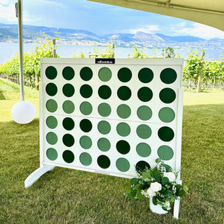 a white giant 4 connect lawn game with faux greenery set on a lawn at a Penticton winery during a wedding