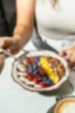 Acai bowl topped with mango, blueberries, strawberries, banana, organic granola, and honey drizzle