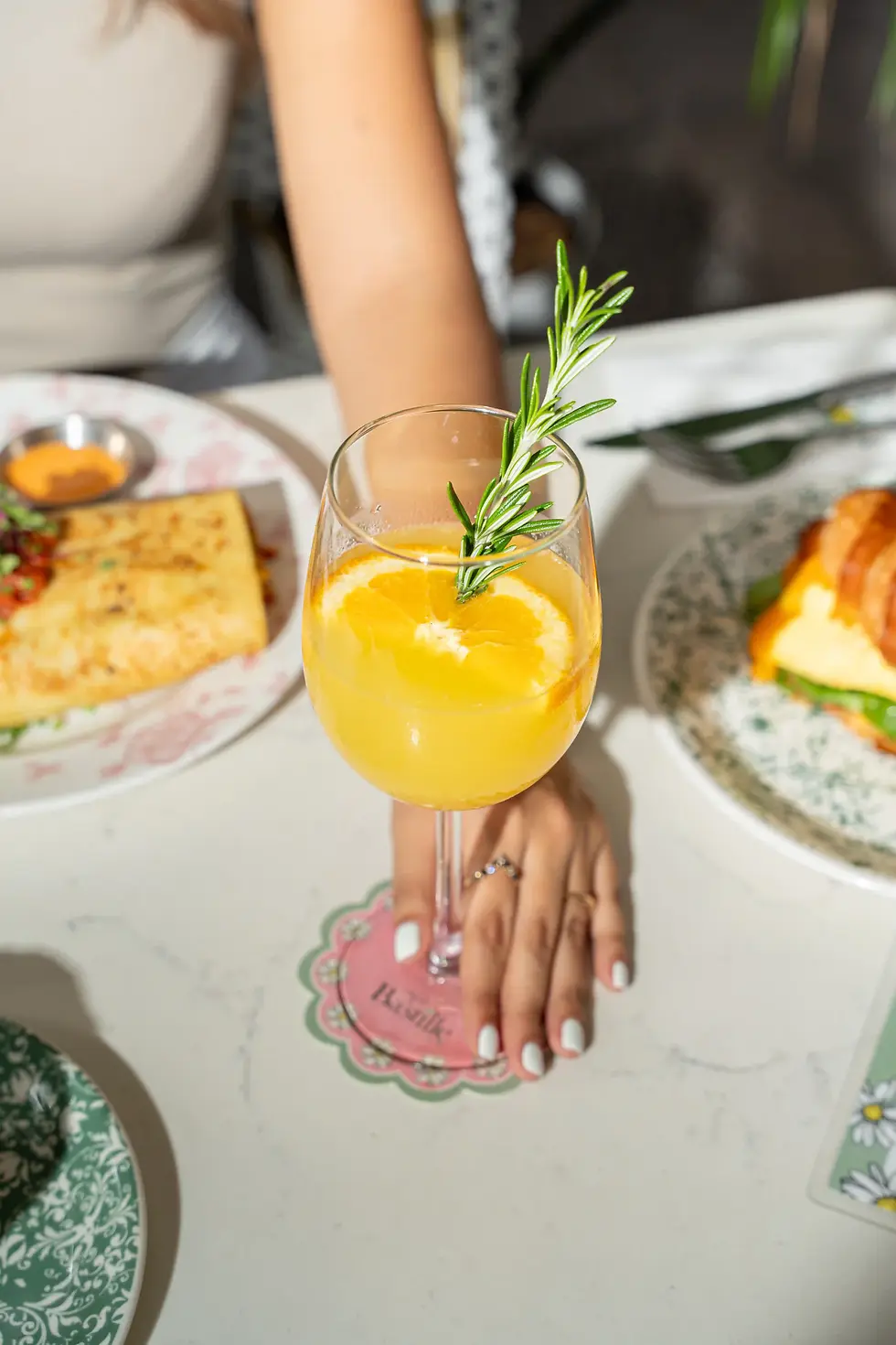 A mimosa with orange slice at the best brunch Fort Lauderdale, served with a Breakfast Croissant and French Breakfast Burrito