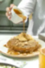 Dulce de leche pancakes topped with bananas, cookie crumble, and caramel sauce drizzle.