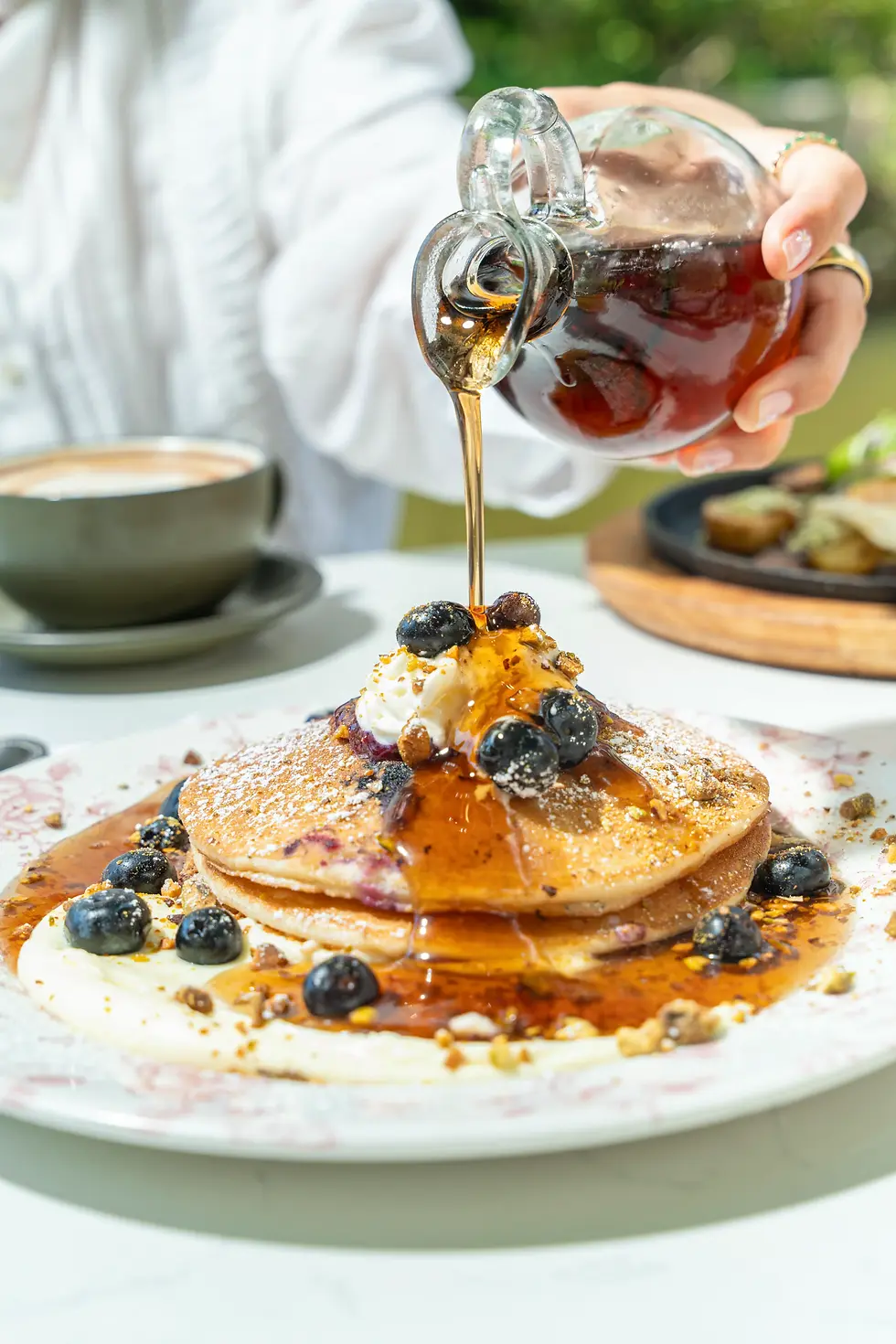 Syrup poured over blueberry pancakes with cream and berries at Café Bastille, kid-friendly brunch Fort Lauderdale