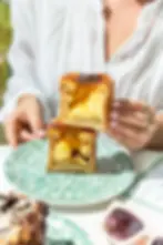 Woman holding a sliced creme brulee croissant with creamy custard filling over a green patterned plate