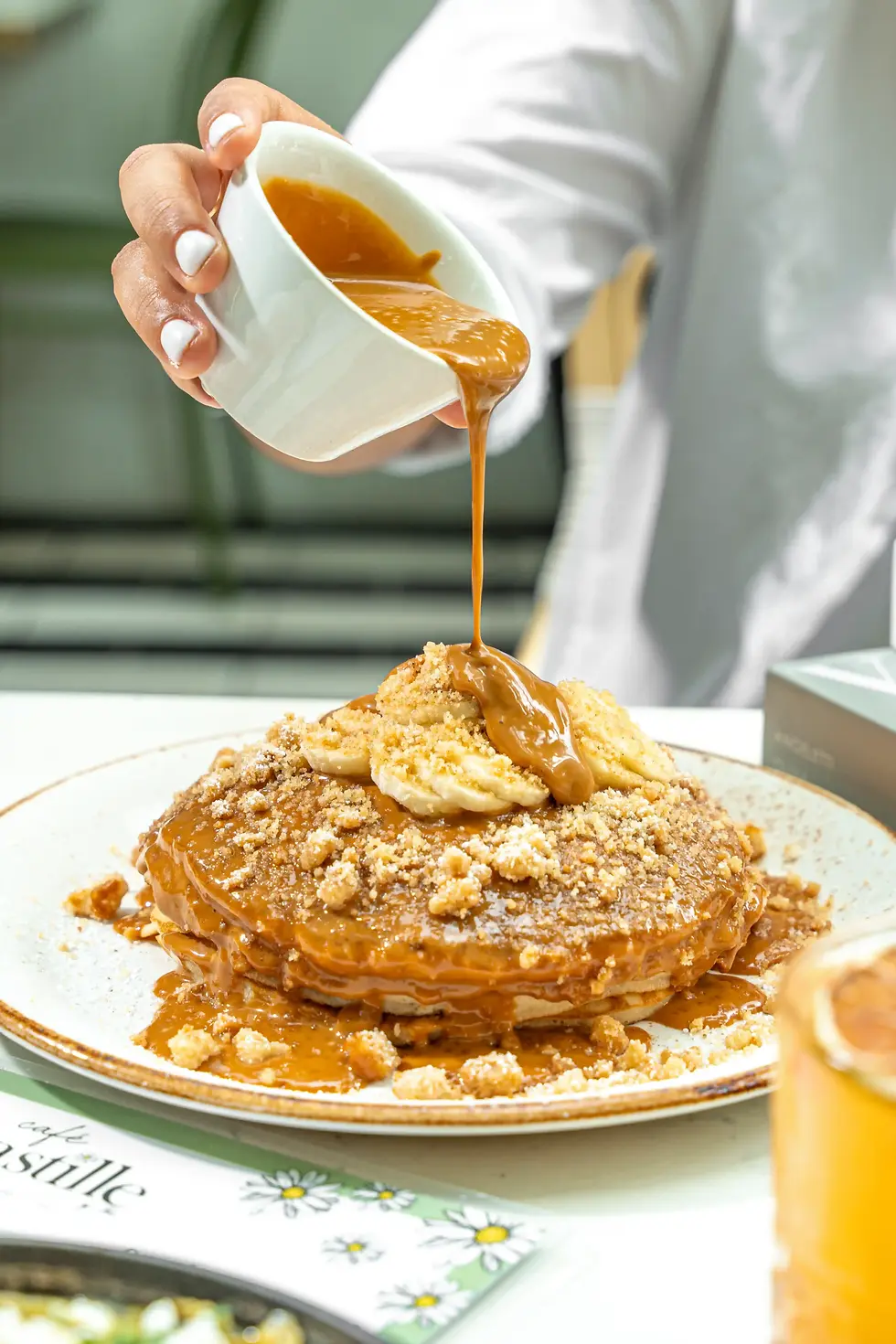 Warm caramel sauce cascading over fluffy pancakes, finished with ripe banana slices and a golden buttery crumble