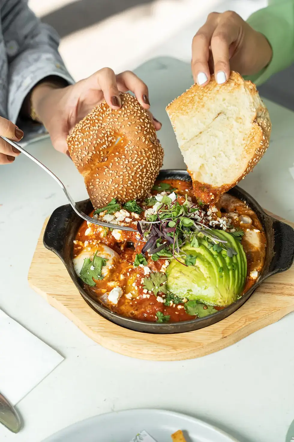 Flavorful Shakshuka with organic poached eggs, tomato-based sauce, crumbled feta, and a side of freshly baked Jerusalem bagel at Café Bastille