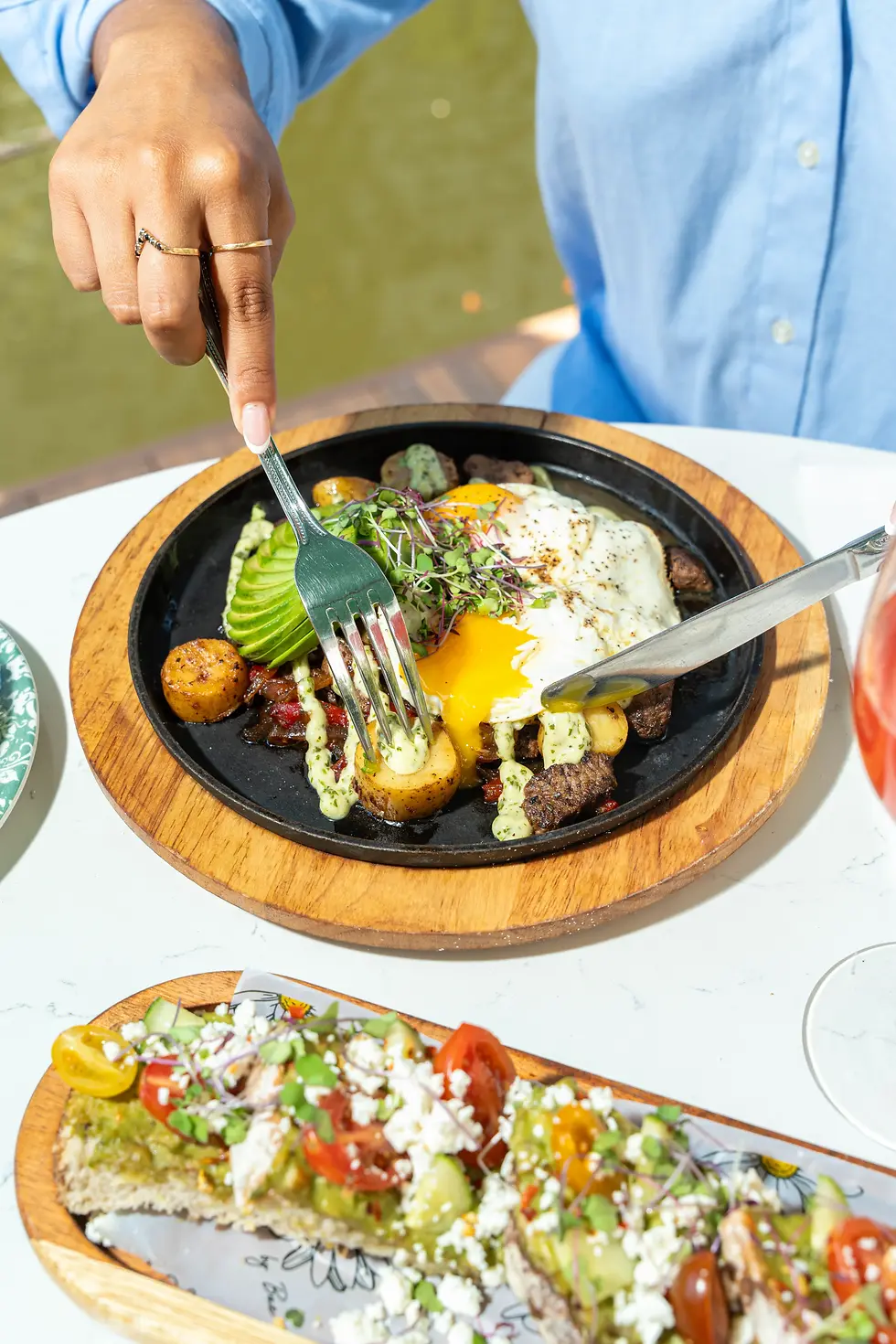 Frank’s Famous Hash with sunny eggs, avocado, and cilantro aioli served on a hot skillet.