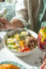 A woman with red nails is enjoying a steak and eggs brunch bowl and a berry cocktail at a brunch restaurant in Miami Beach