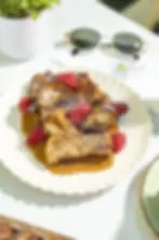 Dulce de Leche French Toast topped with dulce de leche cream and fresh raspberries, served on a scalloped white plate