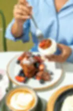 Woman enjoying Crispy French Toast Bites with berries and whipped cream.