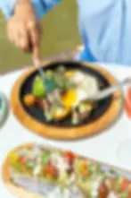 Skillet with sunny egg, avocado, potatoes, and steak beside avocado toast at Café Bastille