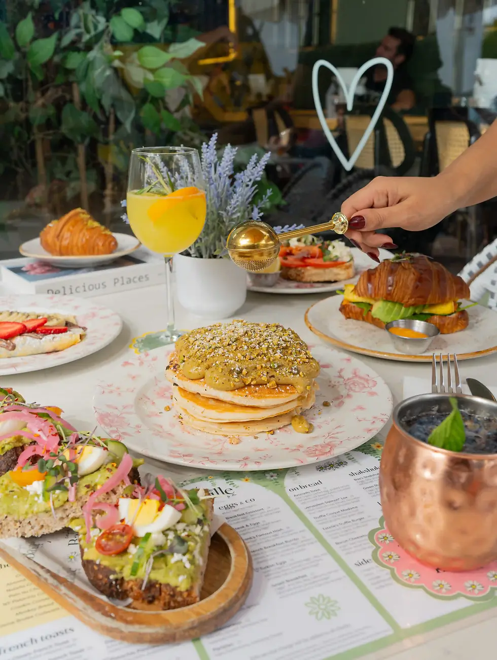 Overhead brunch table spread with French plates orange juice mimosas and flowers on an outdoor patio