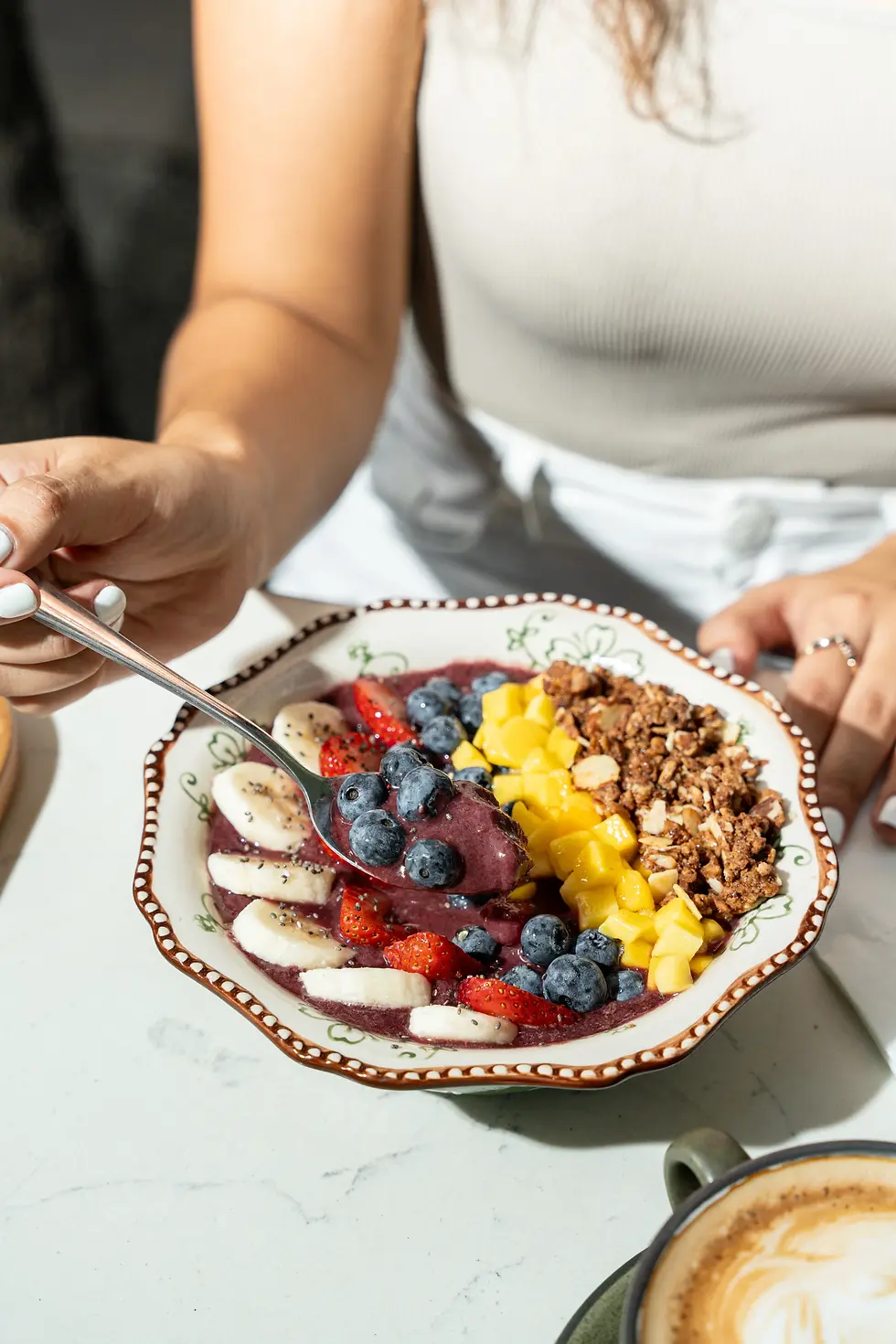 Acai bowl topped with mango, blueberries, strawberries, banana, granola, and honey