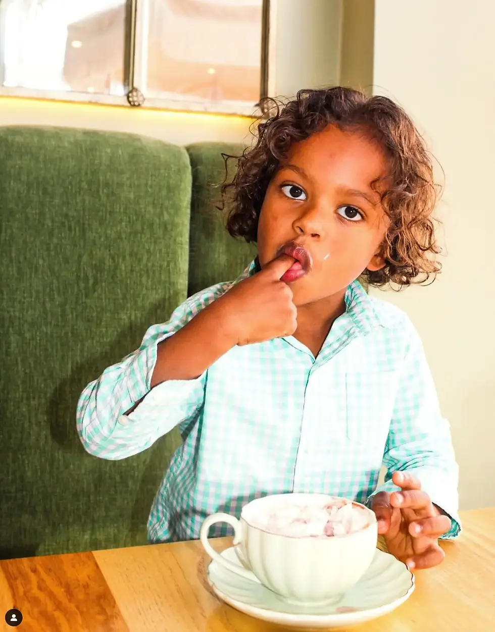Child in a checkered shirt enjoys hot chocolate at a cozy café, capturing the family-friendly vibe of best brunch Miami Beach