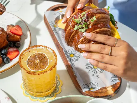 Café Bastille Downtown Miami brunch trio: classic French toast with berries, a citrus cocktail, and a savory egg croissant sandwich — the feel-good plate spread locals trust for the best brunch in Miami.