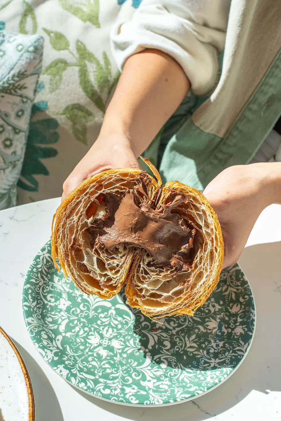 Close-up of a Nutella croissant filled with chocolate hazelnut spread, served on a green floral plate at Café Bastille.