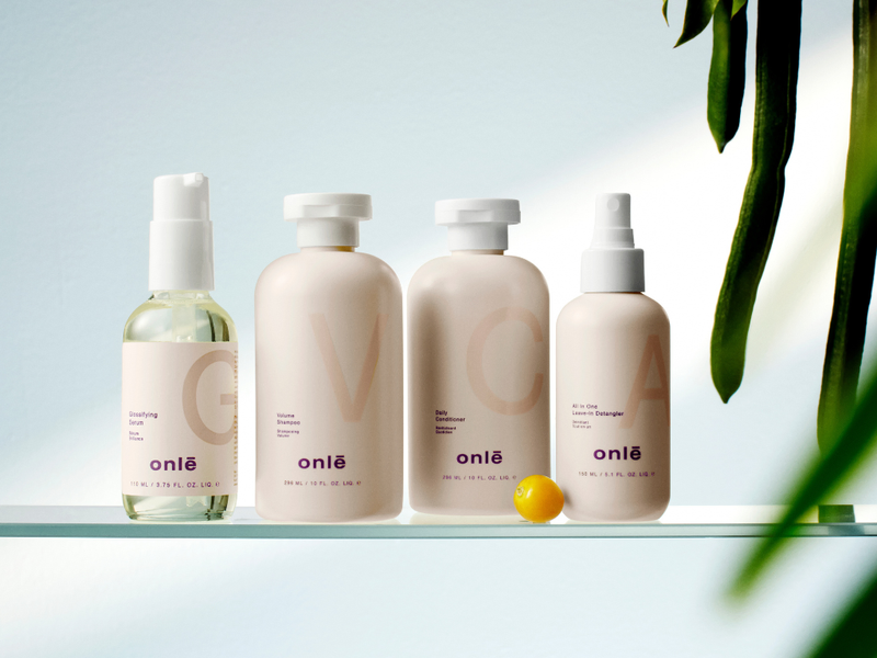 onlē products displayed on a glass shelf with green leaves