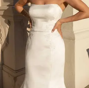 Style D3780 is a strapless fit-and-flare wedding dress that exudes simplicity and elegance. The softly scooped neckline adds a timeless touch to the dress, while the fit-and-flare silhouette enhances the figure and creates a stunning shape. Boning throughout ensures full support, while matte floral lace cascades down the midsection and adds a touch of romance and intricate texture to the design. The combination of satin and lace create a romantic and sophisticated look, making this wedding dress ideal for a bride who wants a classic yet modern look for their special day.