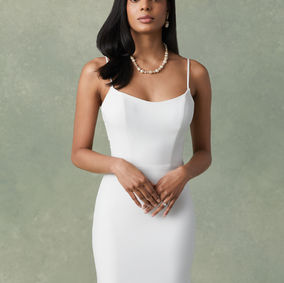 Crepe fit and flare with scoop neckline, spaghetti straps, and low illusion scoop back. Back skirt features tulle and organza overlay that creates a sweep length train. Back embellished with sequined lace appliques and accented with crepe covered buttons cascading to end of train.