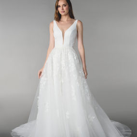 Tulle A-line gown with a plunging V-neckline with a center front illusion inset. Crepe bodice is adorned with matte embroidered lace appliques and chiffon leaf appliques starting at the sides of bust and trickling to the lower portion of bodice. Appliques continue throughout tulle skirt diminishing as they near the skirt hem, Open scoop back is finished with buttons to waist. Complete with a chapel length train