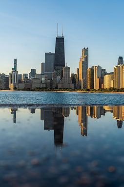 Chicago skyline from North Ave beach, looking at the Hancock building in the early morning, clear blue sky, clear reflection of skyline in the water