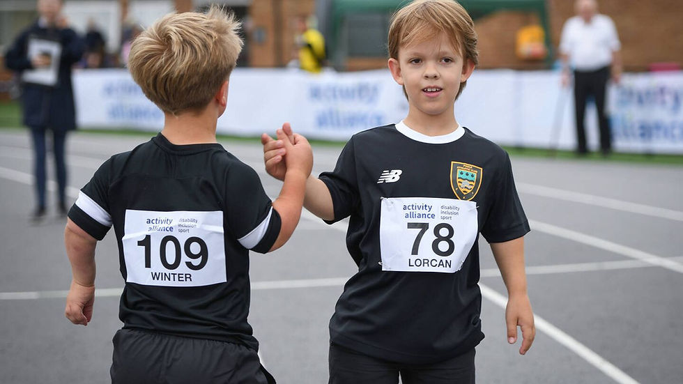 Two boys in black sports kits high-five on a track, wearing race bibs 109 WINTER and 78 LORCAN at an outdoor event.