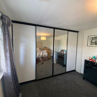 Bedroom with mirrored closet doors and a bed visible in the reflection of it