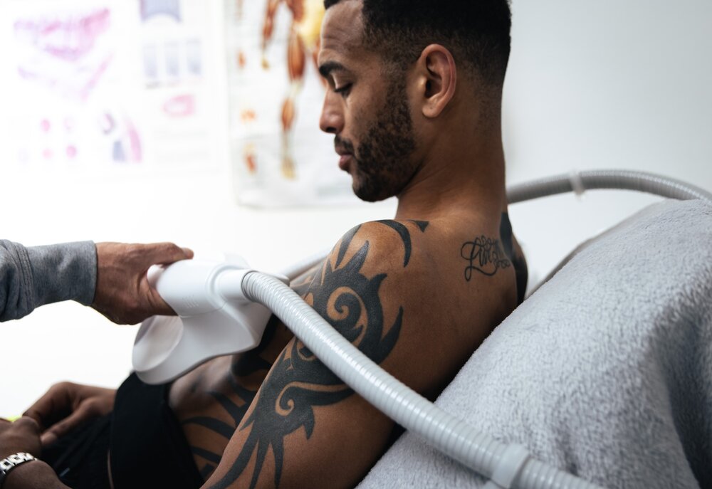 CryoClinic therapist applying cryo wand treatment to athlete's shoulder