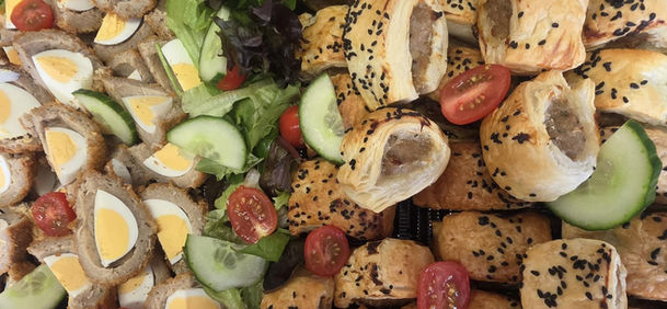 Assortment of savory pastries, Scotch eggs, and salad, a buffet spread by Wonderland Catering.