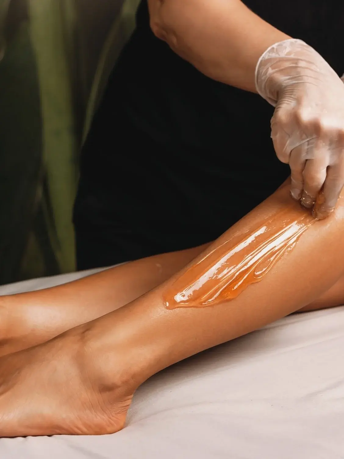 Beautician applying wax to a leg, smooth skin treatment. La Monica Beauty & PMU.