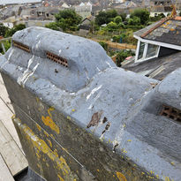 Grey painted structure with sea view background, Roofing South West in scene.