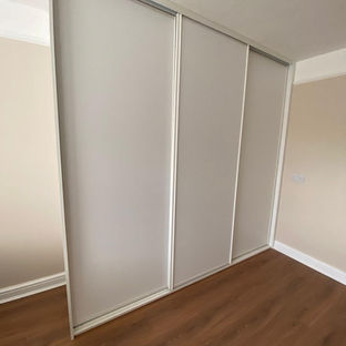 A clean, white sliding door closet in a room with hardwood floors