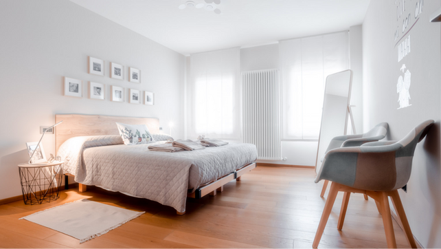 Vista d’insieme della camera padronale con letto matrimoniale, pavimento in legno e luce naturale, nella casa vacanze Una Chicca a Valdobbiadene. Scatto di Mattia Mionetto – @mattiamionetto