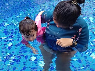 Focused student engaged in swimming lessons, being carried by a supportive coach.