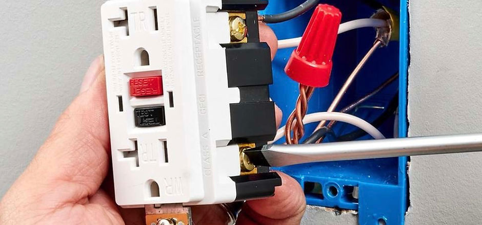picture of a person installing a GFCI outlet. he has a screwdriver lighting a screw