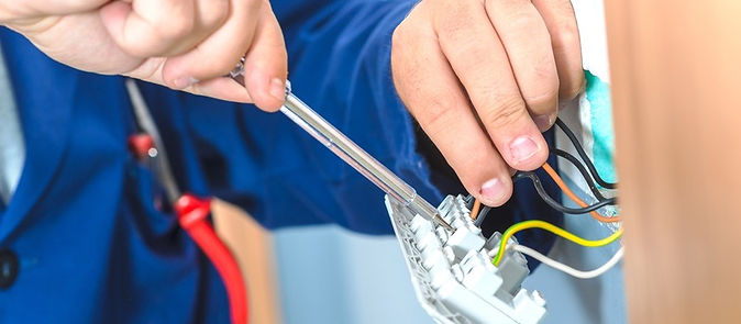 Electrician using a screwdriver to secure wiring to an outlet, Electrical Services