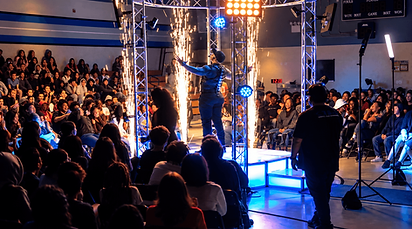 K–12 motivational speaker TMoore The Motivator performing on stage with cold spark effects during a school assembly.