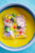 Yellow soup dish with flowers and caviar
