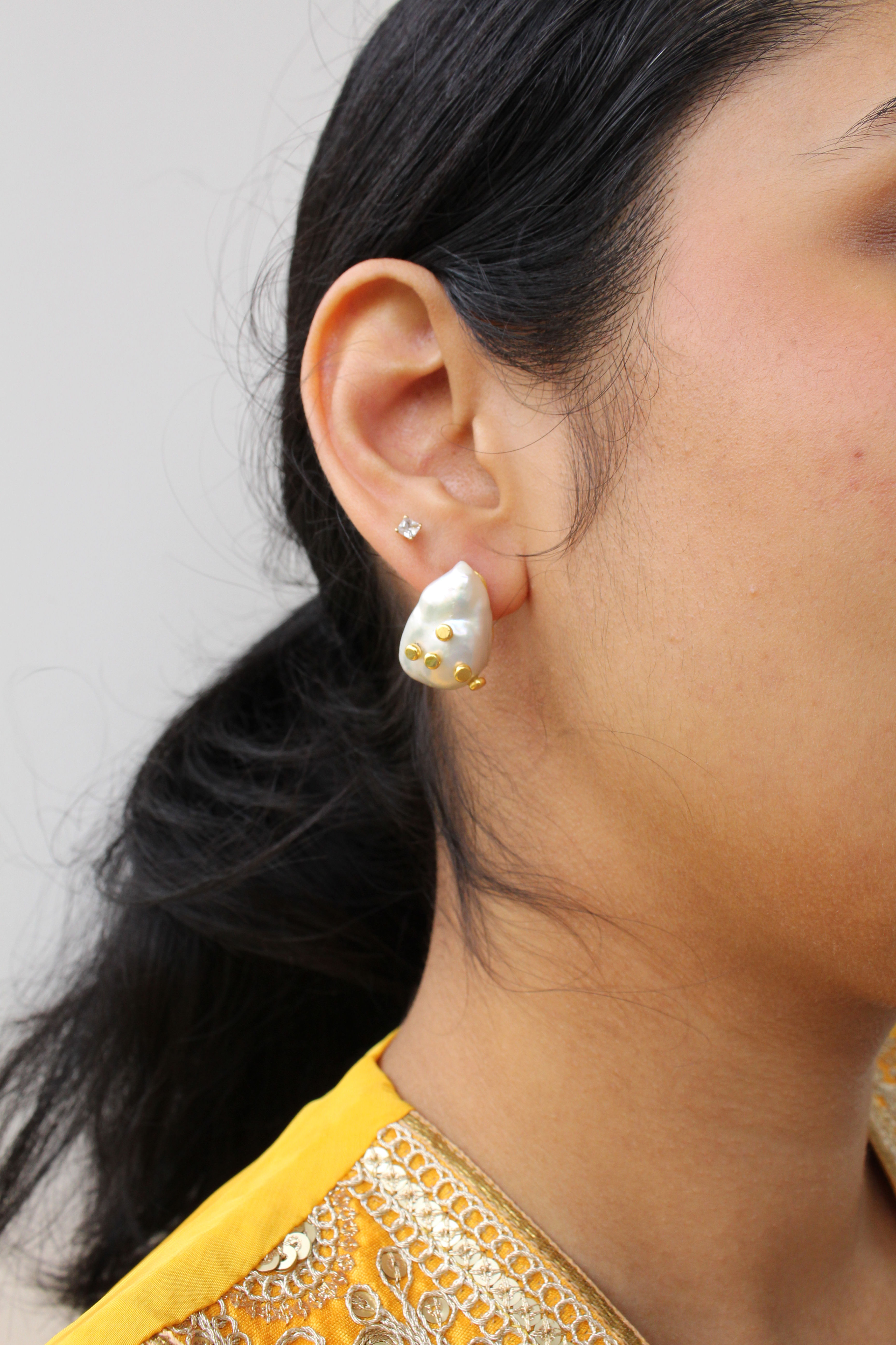 Elegant earring featuring a shimmering blue-grey labradorite stud, accented with tiny real pearls and a dangling baroque pearl adorned with randomly placed tiny gold flakes