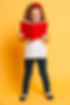 Picture of concentrated little pretty girl standing isolated over yellow background readin