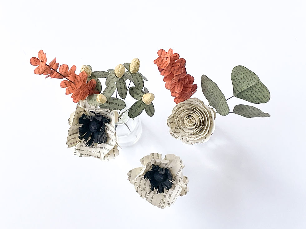 top view of book page floral arrangement in earthy autumnal tones of cream, green, orange and yellow