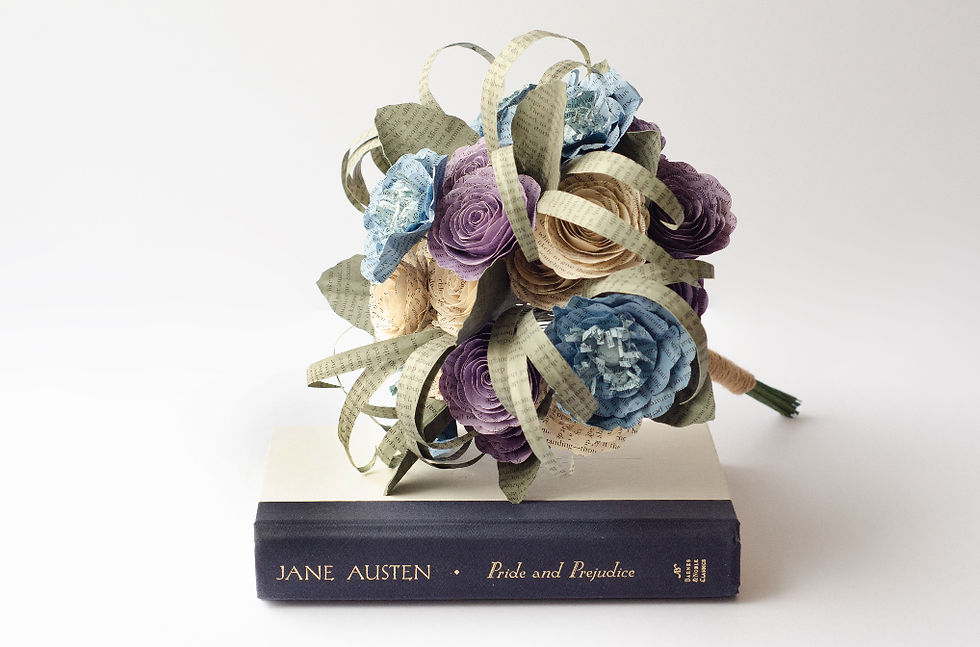 Paper flower bouquet made from book pages rests on Jane Austen's Pride and Prejudice, in pastel purple, blue, and cream, made with poppies, roses and lily grass.